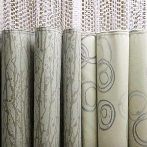 Detailed close-up of decorative curtains featuring patterned fabric with abstract designs and lace trim. Neutral tones create a soft, elegant appearance.