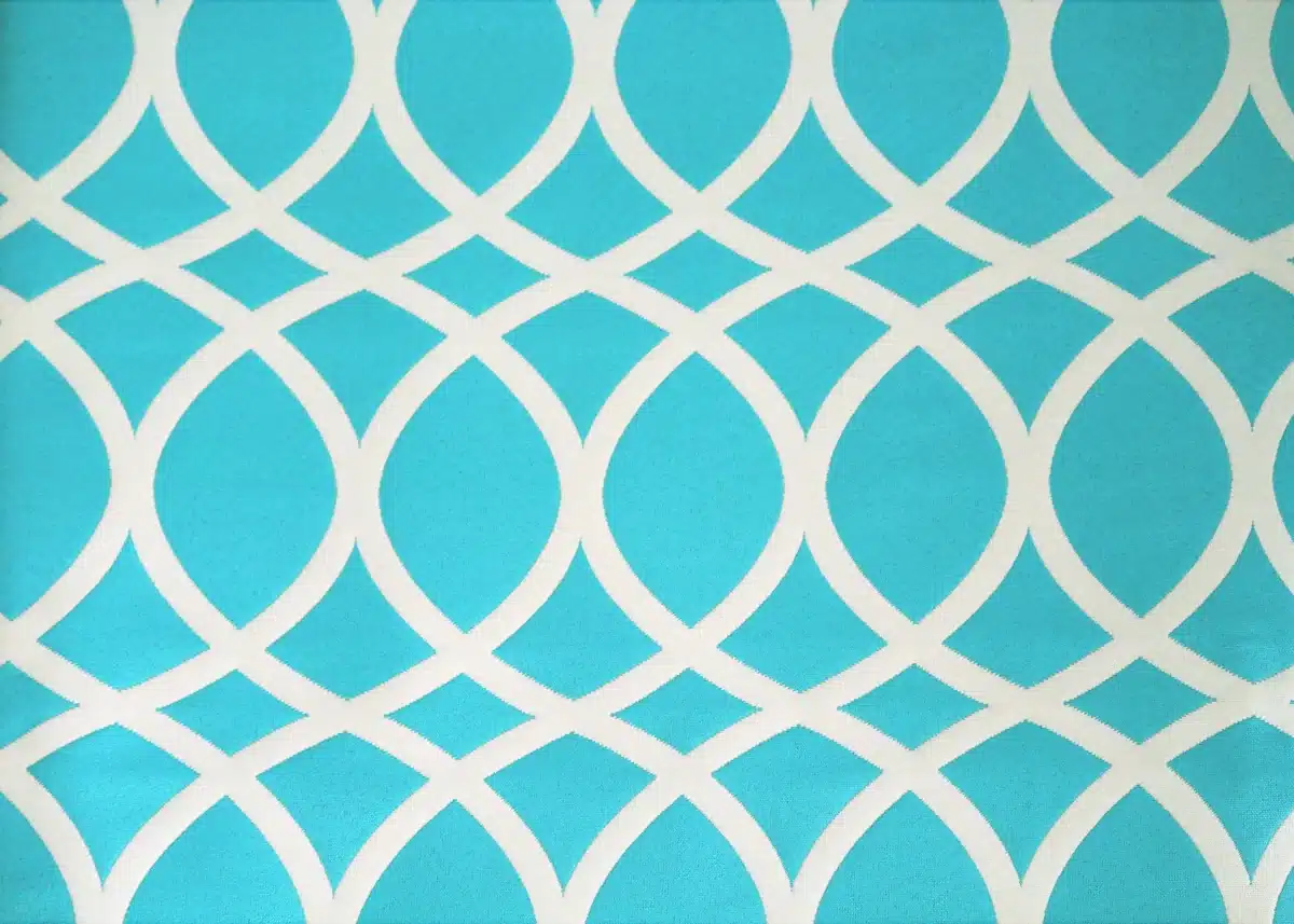 Geometric pattern with white overlapping arcs on a bright turquoise background, creating a lattice-like design with symmetrical shapes.