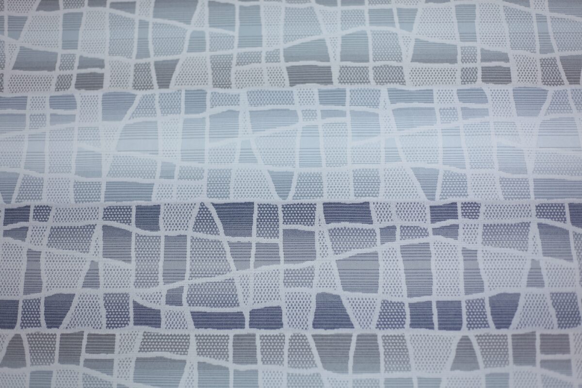 Abstract pattern featuring irregular white shapes on a gray and blue background, resembling stylized mosaic or stained glass design.