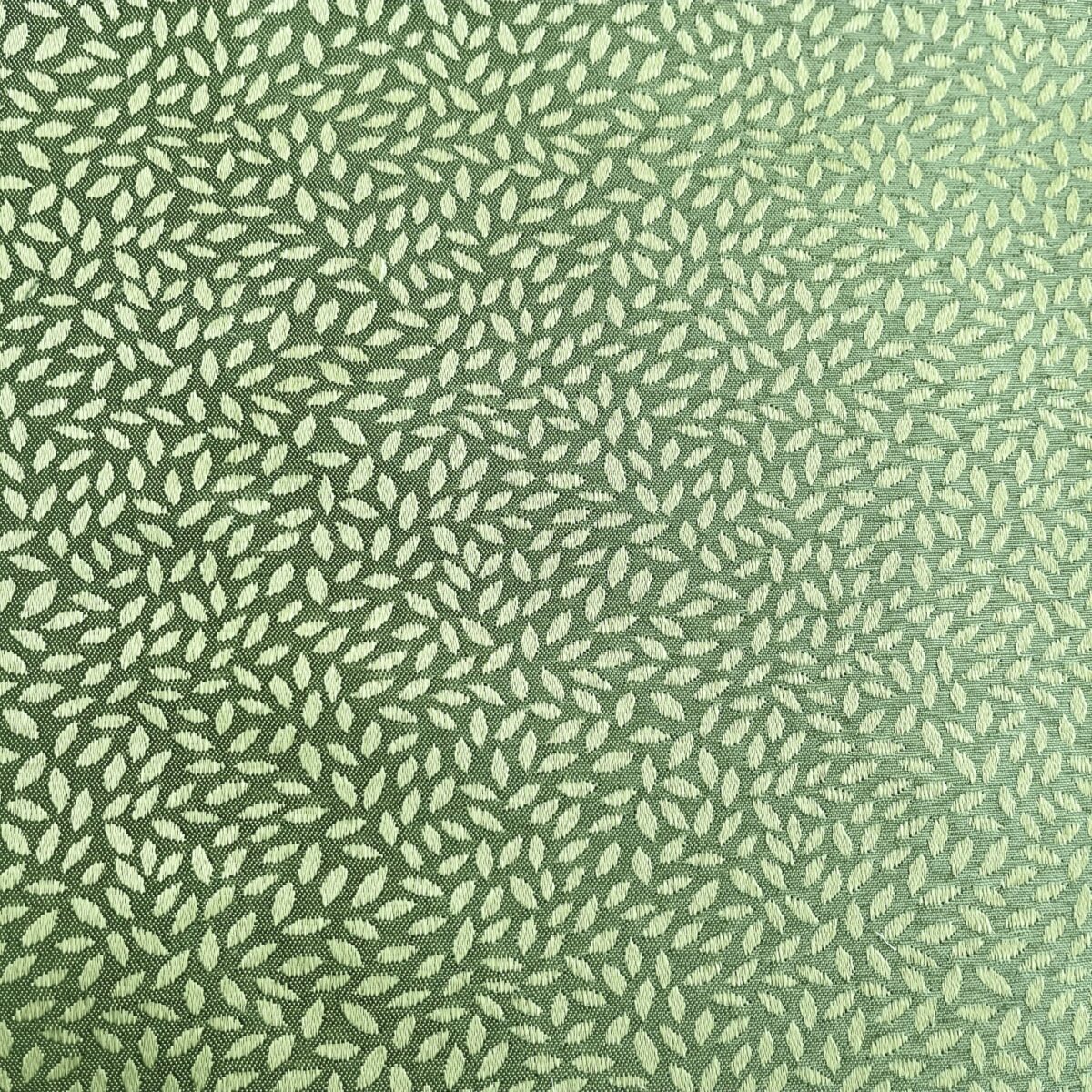 A close-up image of a green fabric with a repetitive, textured leaf pattern design. The design features various shades of green.