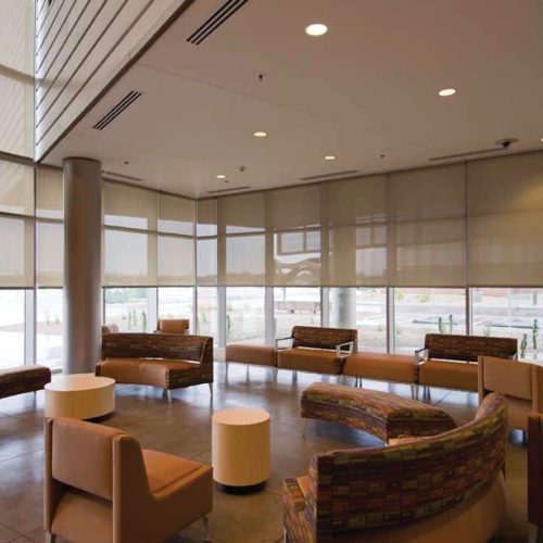 Modern, spacious lobby with large windows and stylish, curved seating. Natural light filters through blinds onto the polished floor, creating a welcoming atmosphere.